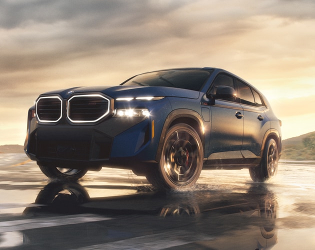 Heroic shot of the BMW XM Label parked on a beach at sunset