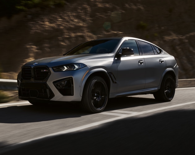 Side angle shot of the BMW X6 M Competition cruising down a road