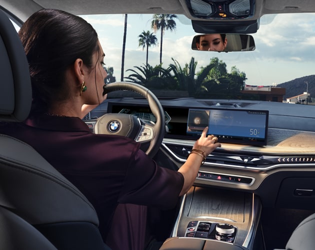 A driver interacts with the iDrive Operating System in a BMW X7 SUV