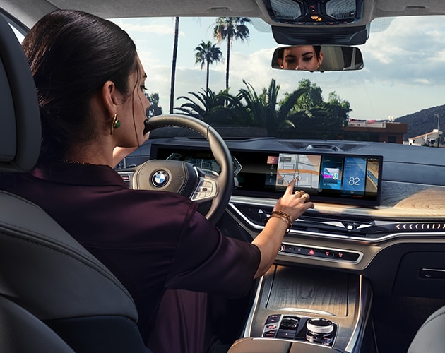 A driver interacts with the latest iDrive 8 Operating System in a BMW X7 SUV