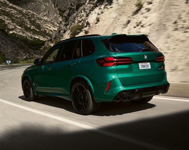 Rear view of the BMW X5 M cruising down a windy, mountain road