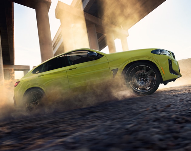 Dust rises through the air as the X4 M Competition drives off road