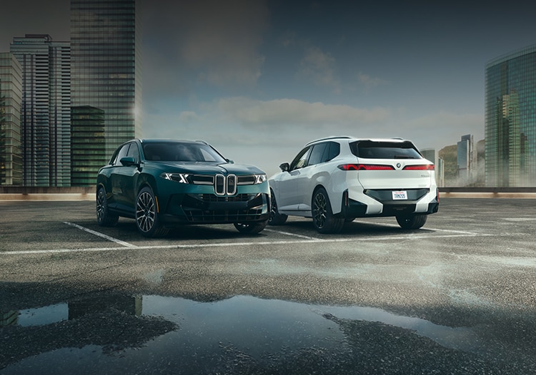Two BMW X5 SUVs parked on a rooftop parking area in an urban setting