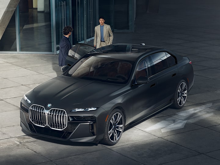 A driver opens the door for a gentleman entering the rear seat of a 2025 BMW 7 Series Sedan