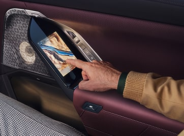 A passenger uses the touchscreen controls mounted in the doors of the 2025 BMW 7 Series Sedan