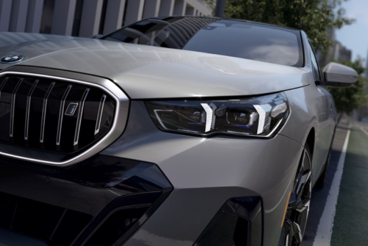 Dramatic zoomed-in front view of the headlights and available Illuminated Kidney Grille of the BMW i5 eDrive40