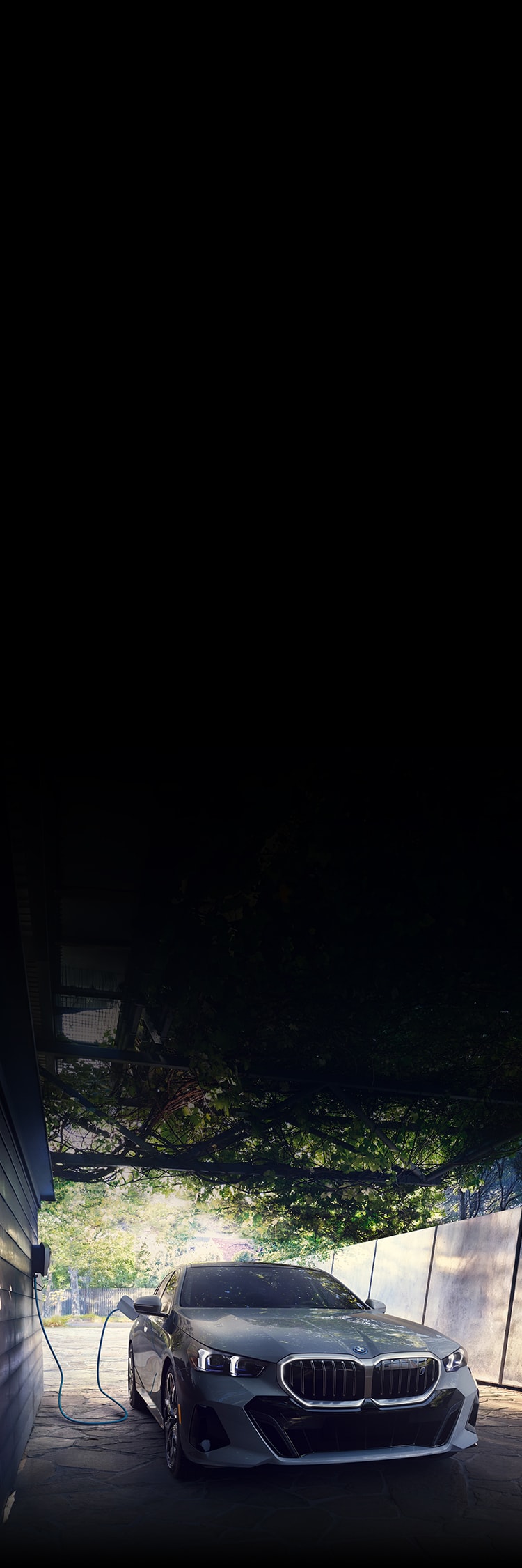 The all-electric i5 eDrive40 charges on a driveway with the BMW Wall Charger