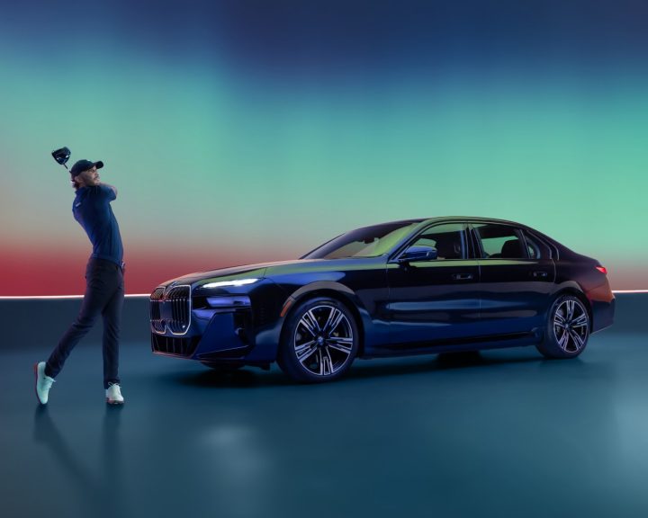 Max Homa swings his golf club near the BMW i7
