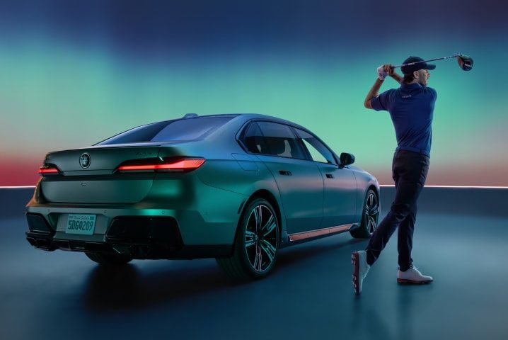 Rear view of the BMW i7 and Max Homa completing his golf swing