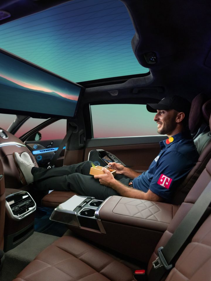 Max Homa relaxes with his feet up in the passenger seat of a BMW i7