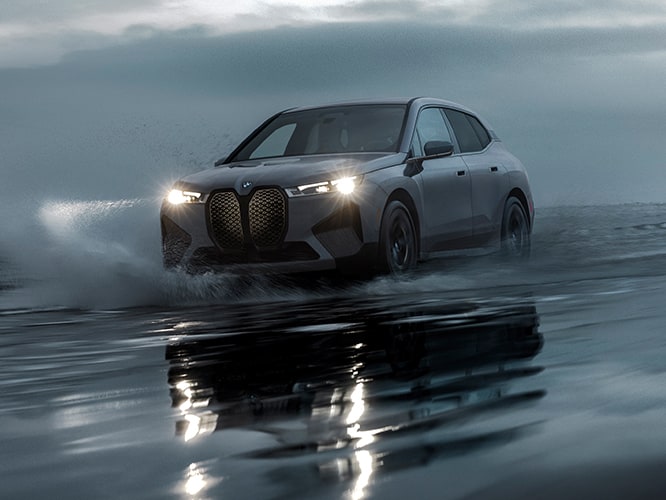 The BMW iX M60 SUV driving through saltwater