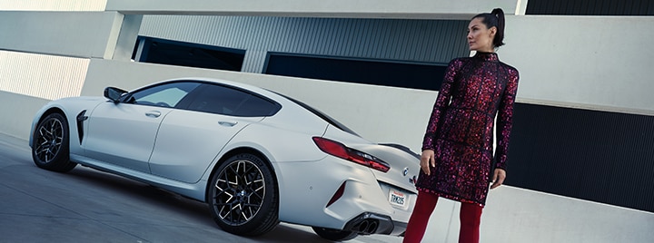 A driver poses behind the 2025 BMW M8 Competition Gran Coupe