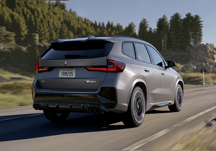Rear view action shot of X1 driving along highway with trees in the background