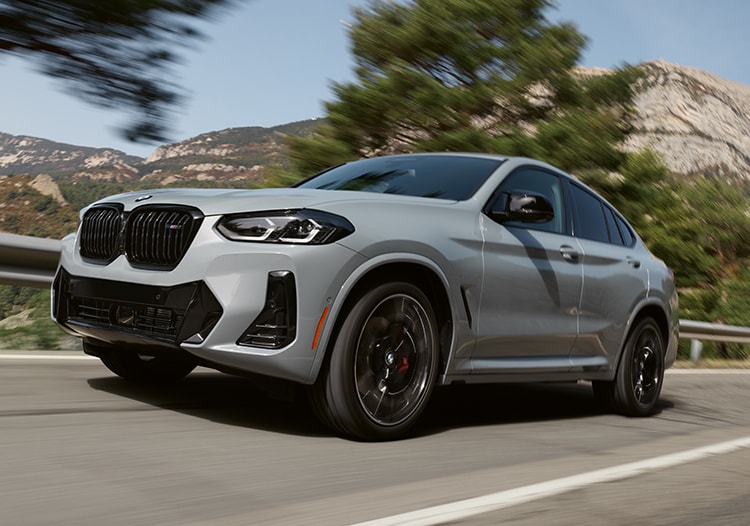 Dynamic shot of the 2025 BMW X4 driving on a mountainous road
