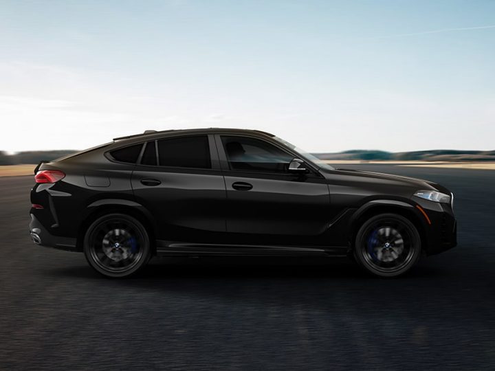 Side profile of a 2026 BMW X6 Coupe SUV parked in a rural setting