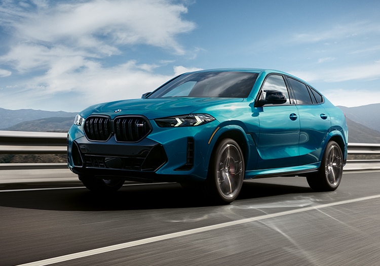 3/4 shot of the 2024 BMW X6 in motion on a rural highway