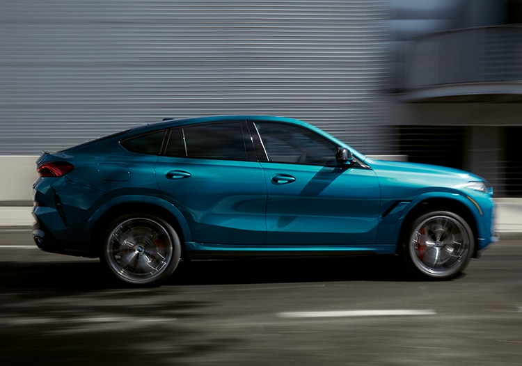 Profile of the 2024 BMW X6 in motion on a city street